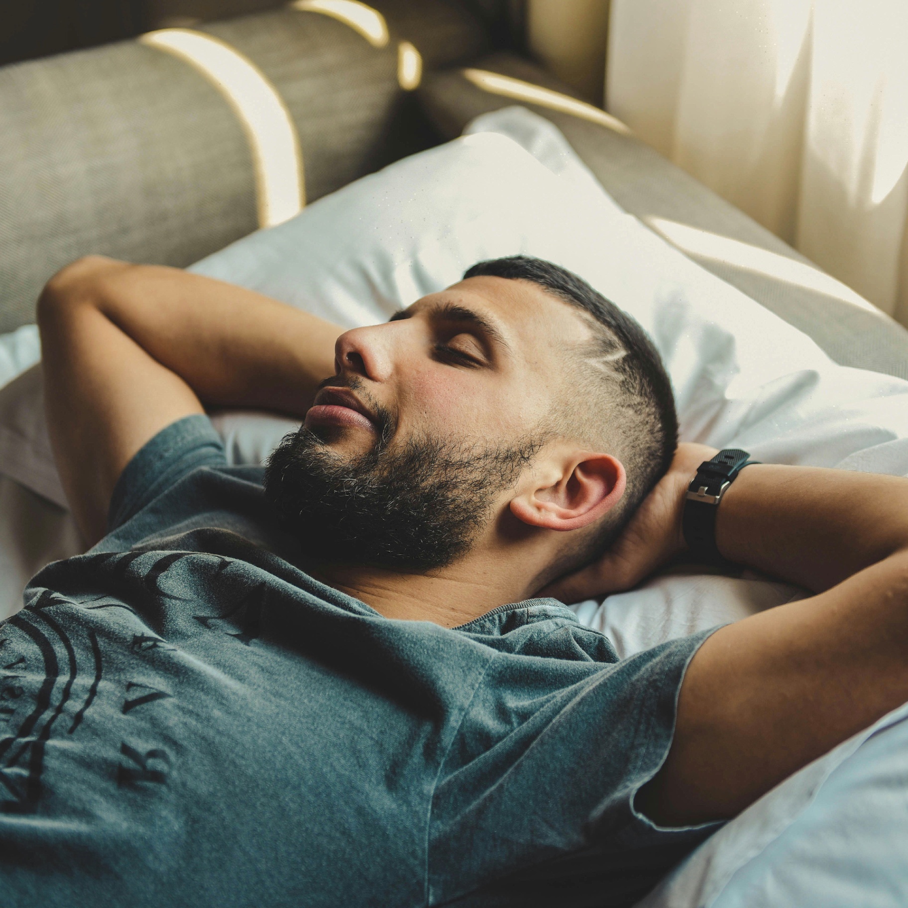 Man resting peacefully on a pillow with warm morning light behind him