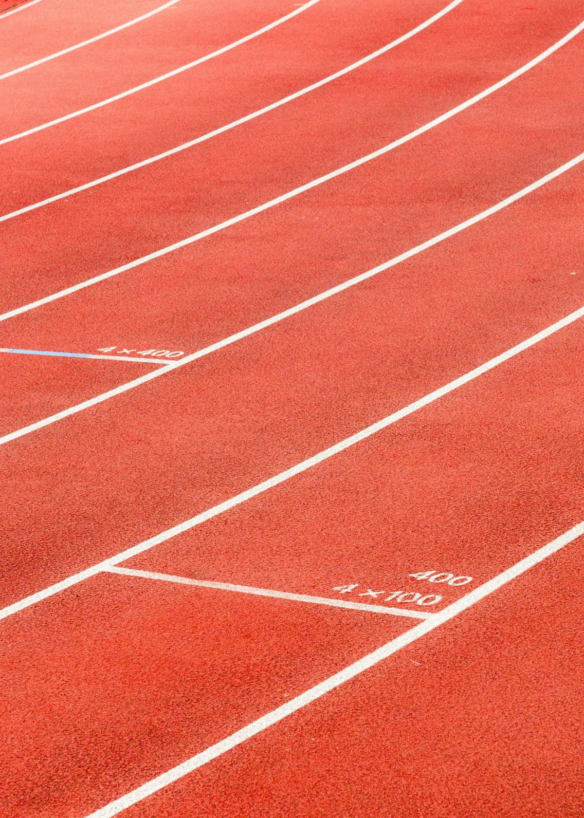 Close view of the white lane markings and relay markers on a red athletics track
