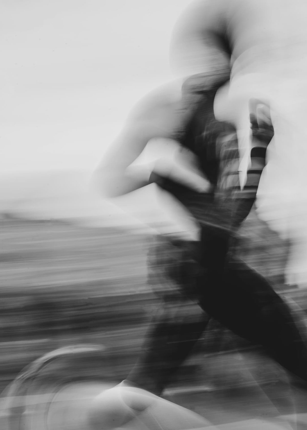Black and white motion-blurred photograph of a runner moving past the camera