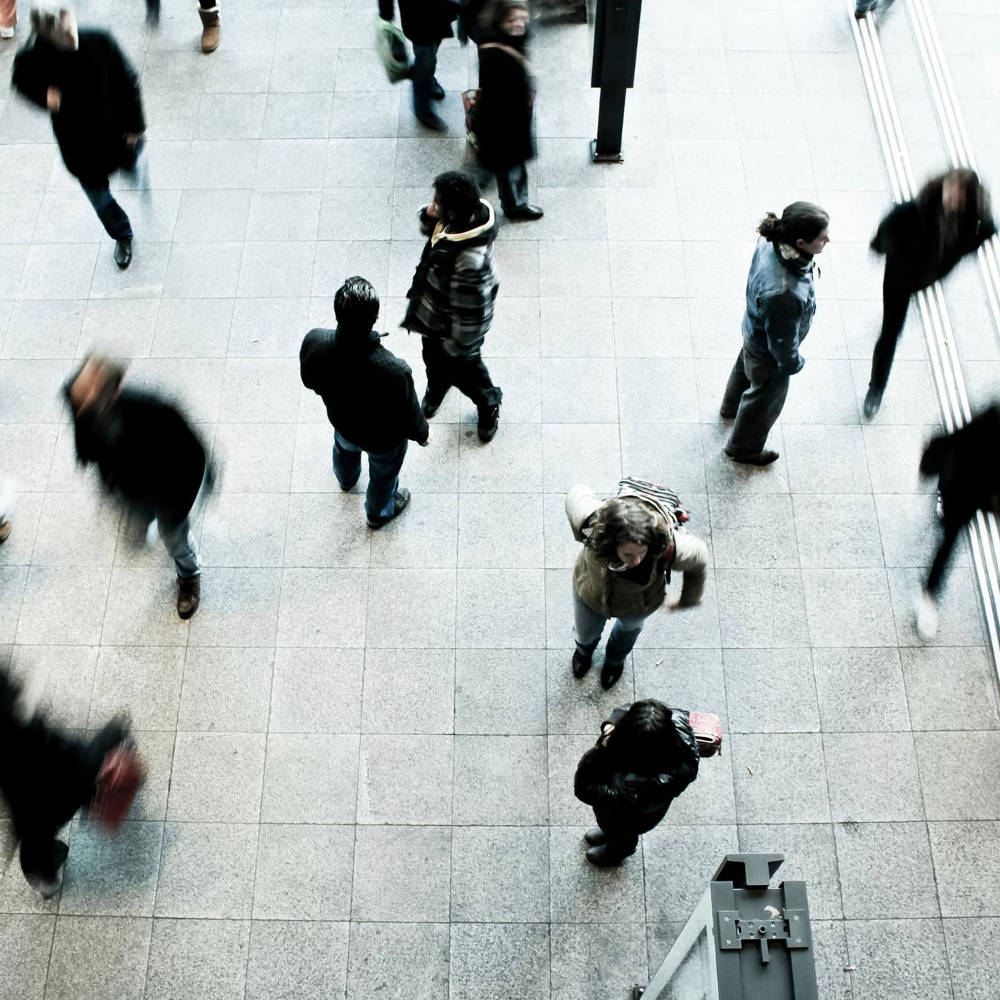 Overhead view of people walking in different directions across a bright paved plaza
